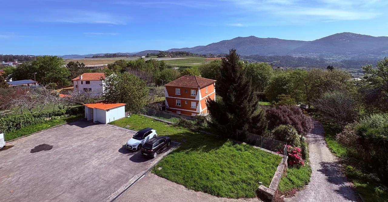 Aparcamiento y jardín de El Bosque con montañas al fondo