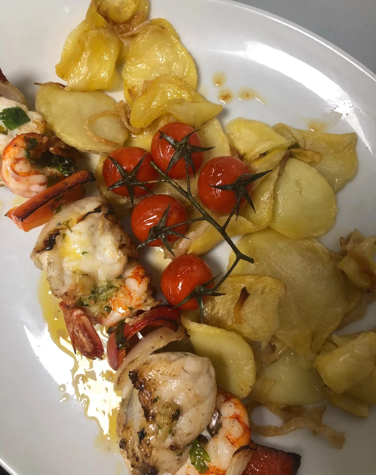Plato de pescado con gambas, tomates y patatas del restaurante El Bosque