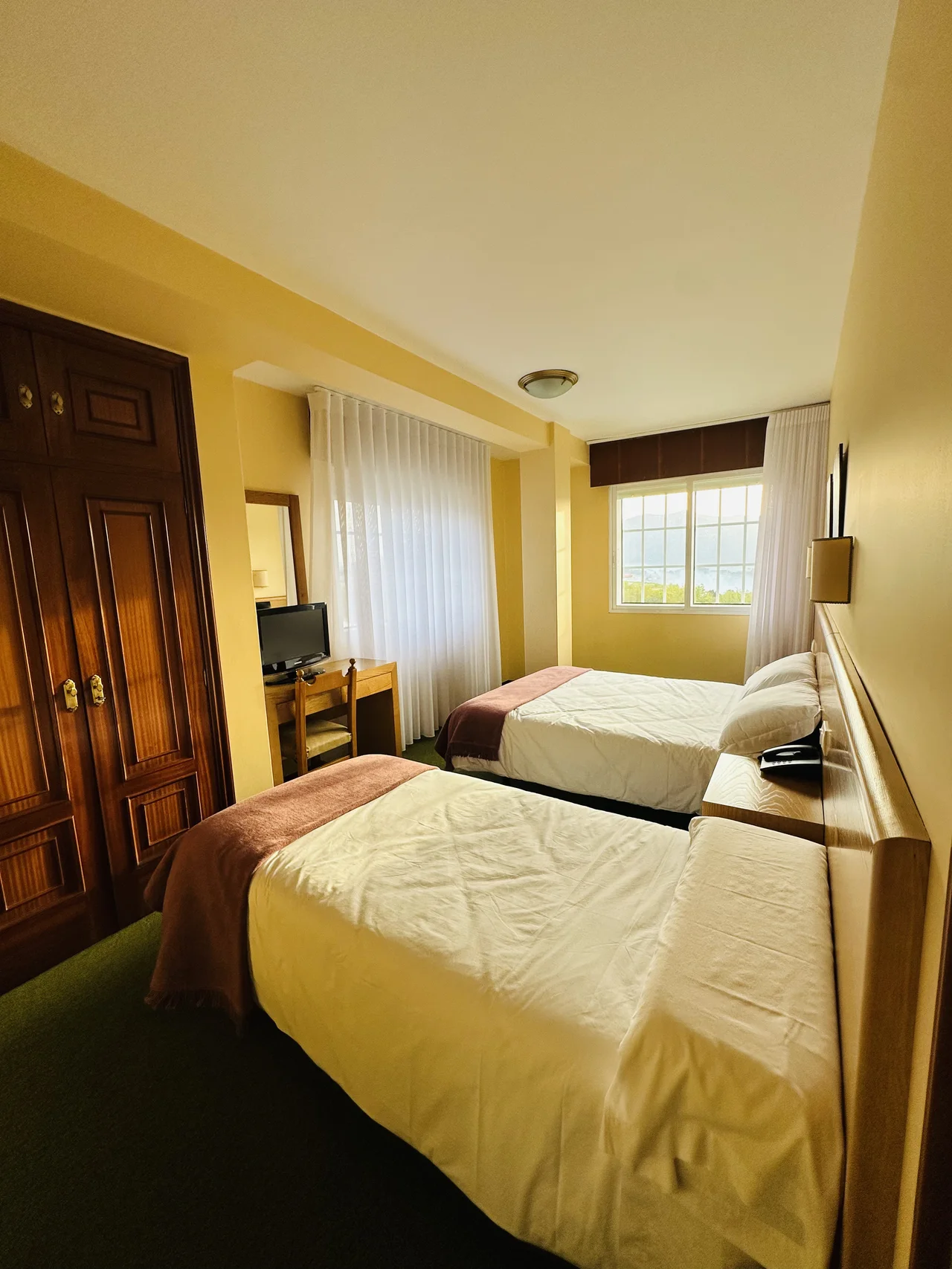 Habitación de El Bosque con dos camas, armario y luz de la ventana