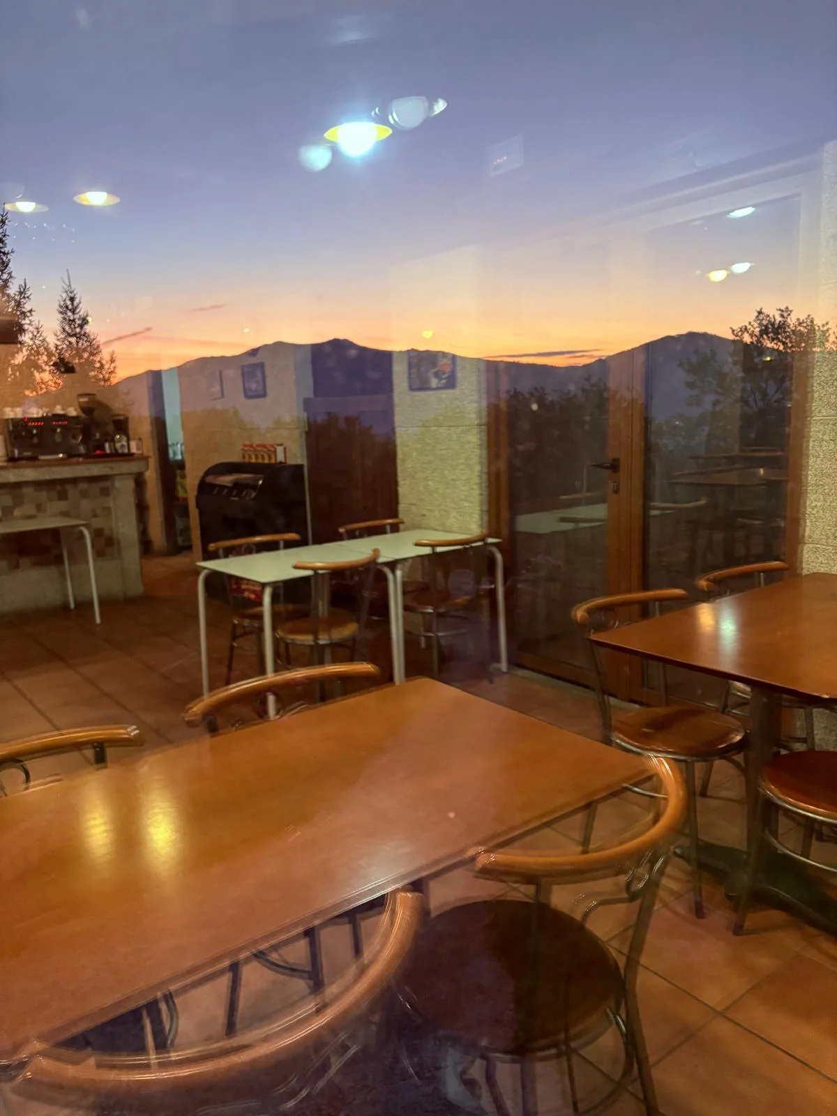 Mesas junto a las ventanas del comedor de El Bosque al atardecer