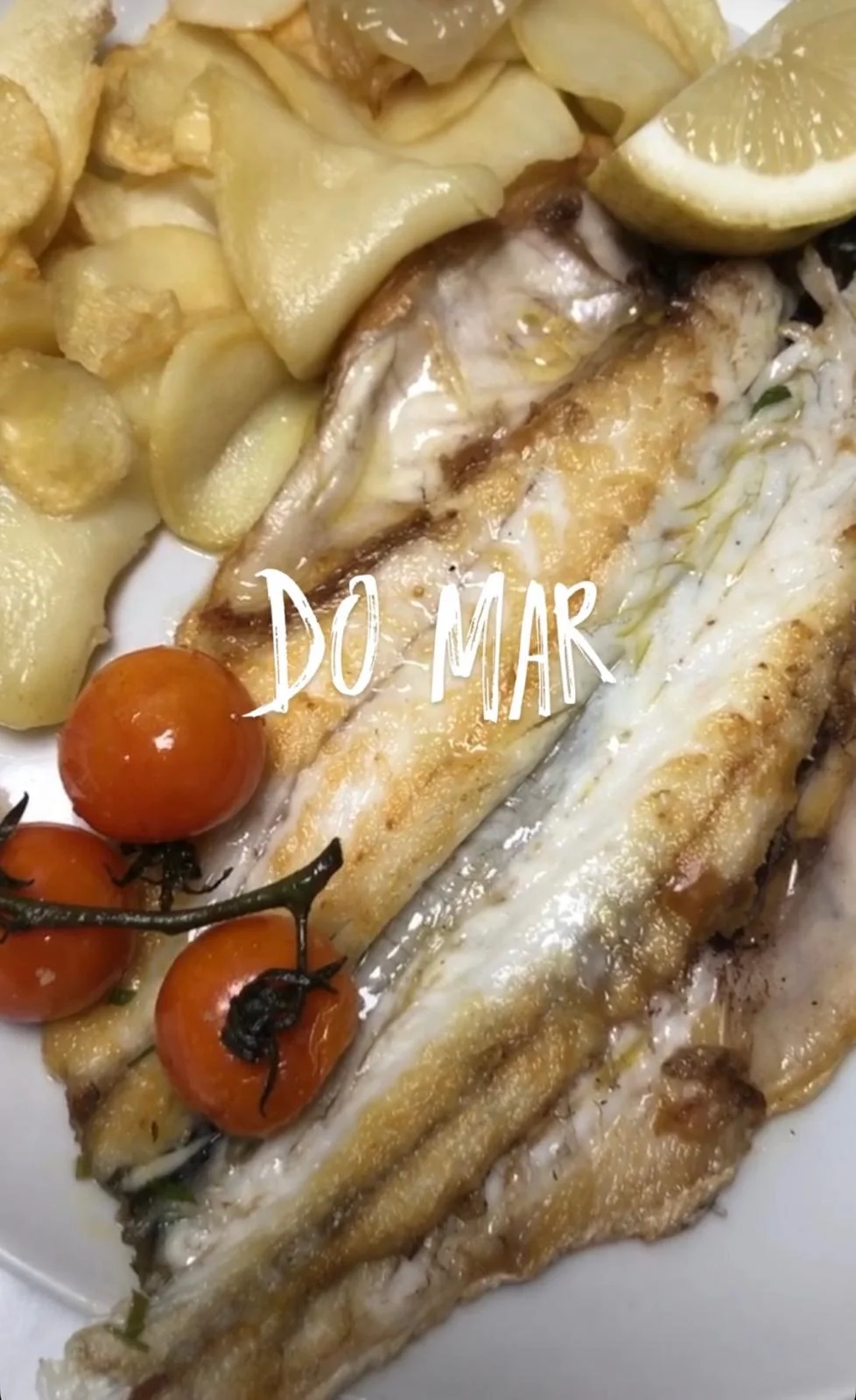 Pescado con patatas, tomates y limón en una fotografía del restaurante El Bosque