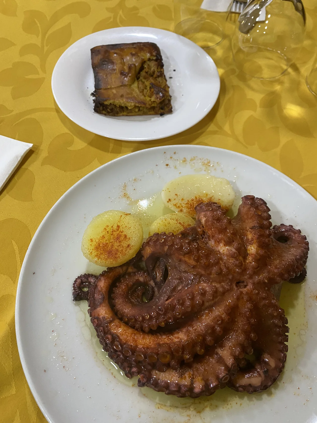 Plato de pulpo y patatas junto a otra preparación en un plato pequeño