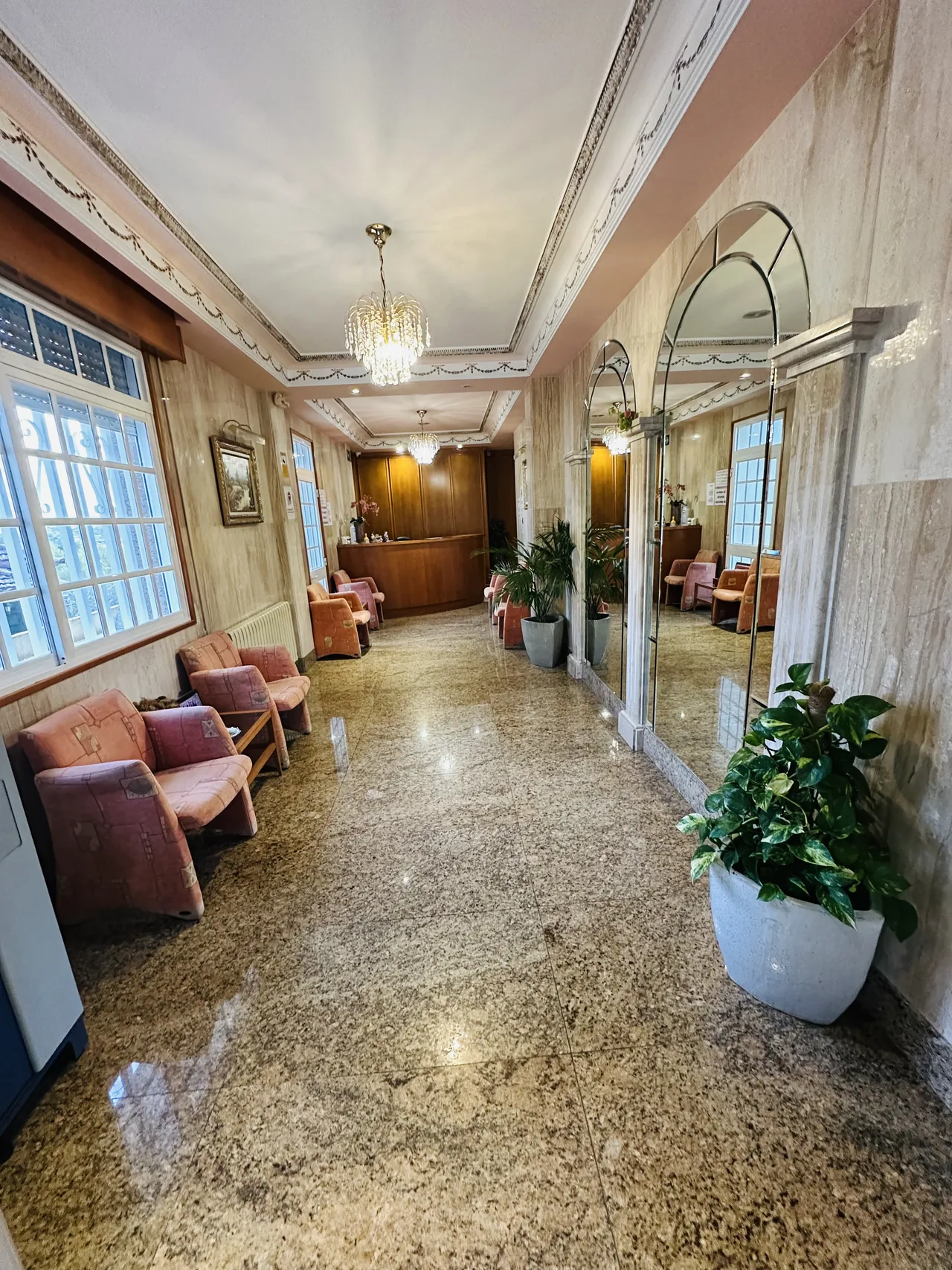 Salón de entrada con sofás, plantas y espejo en el Hotel El Bosque